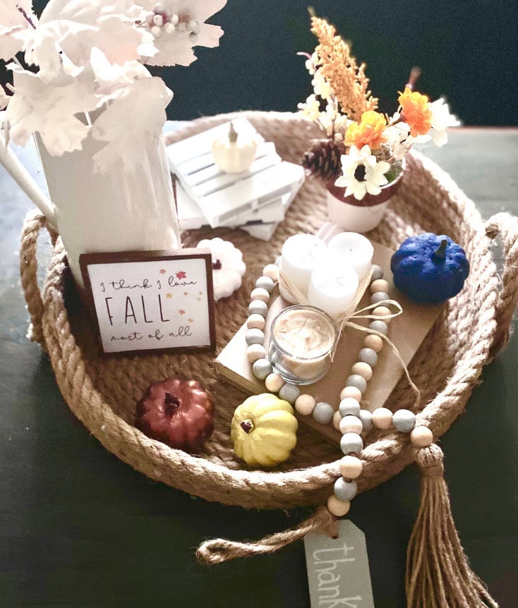 Cozy decorative fall centerpiece with candles, mini pumpkins, and floral accents in a woven basket, ideal for autumn-themed home decor and creating a warm, inviting atmosphere.