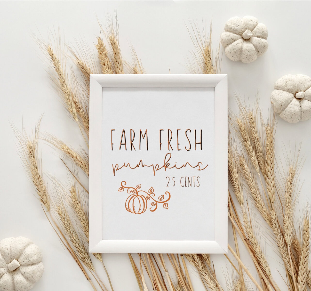 Vibrant farm fresh pumpkin sign with handwritten style lettering and pumpkin illustration, surrounded by dried wheat and small decorative pumpkins, perfect for autumn or fall decor.