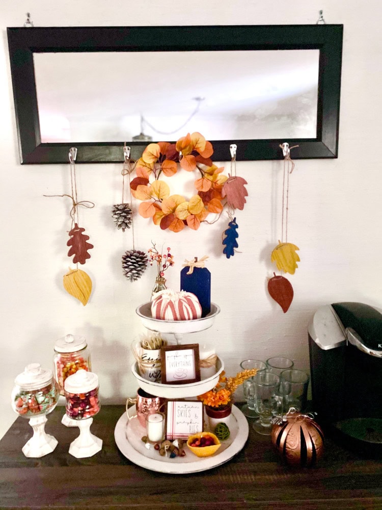 Vibrant autumn-themed home decor display with a leaf and pinecone garland, colorful candy jars, and cozy seasonal accents, perfect for fall or Thanksgiving celebrations.