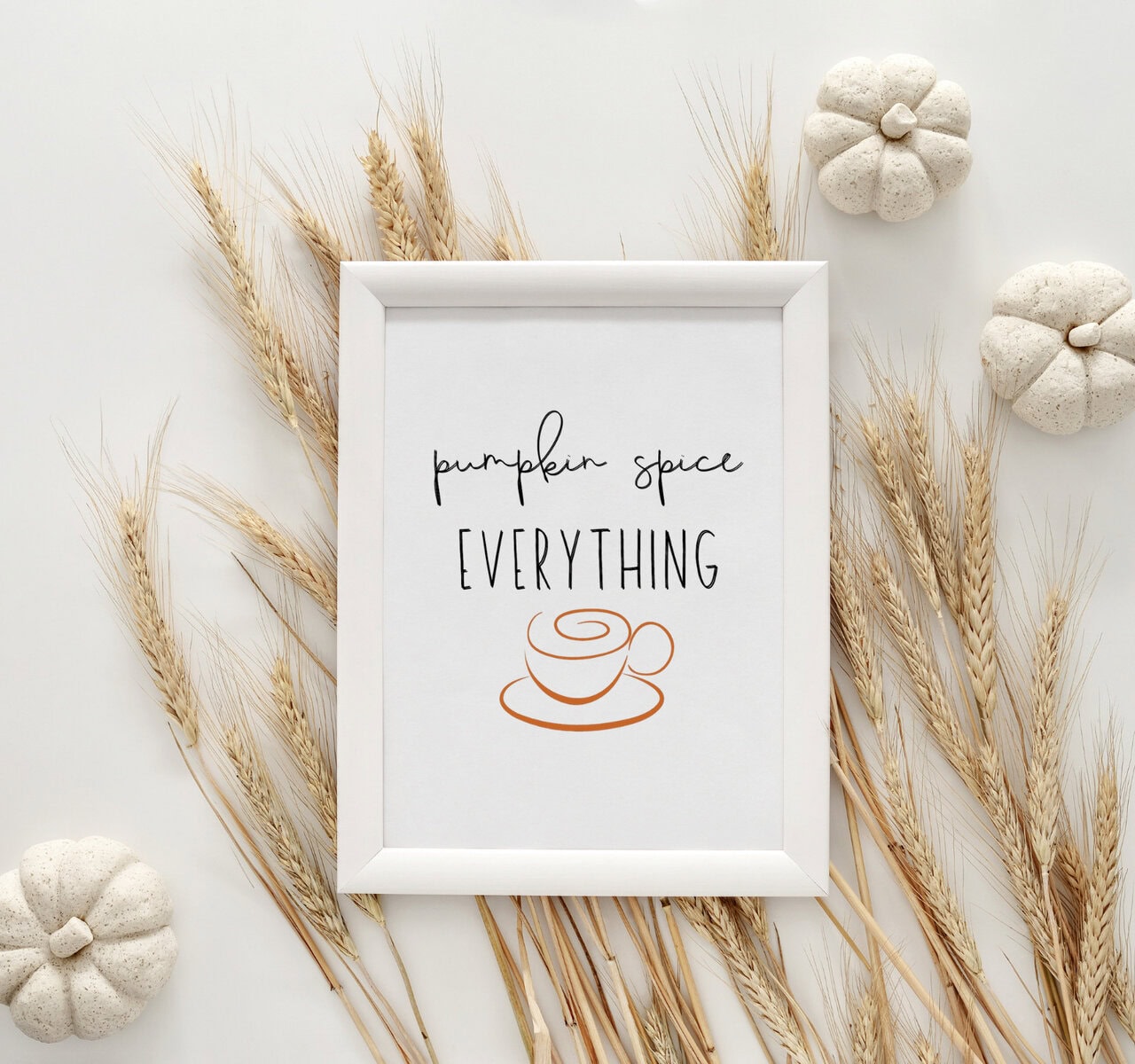 Elegant farmhouse-style decor with a white framed sign reading "Pumpkin Spice Everything" surrounded by dried wheat stalks and small decorative pumpkins, perfect for autumn or cozy home accents.