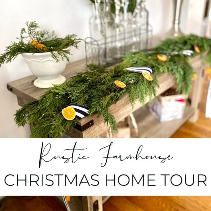 Lush Christmas greenery garland with dried orange slices and navy-and-white striped ribbons displayed on a rustic wooden table for holiday home decor.