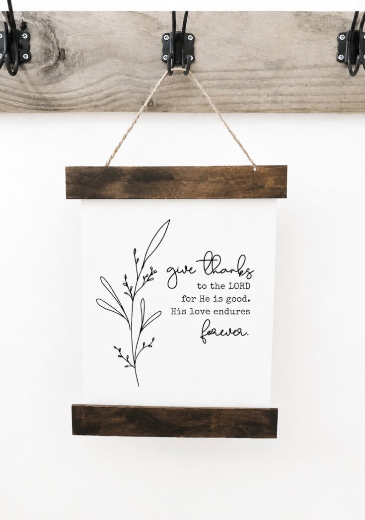Rustic farmhouse wall decor with a hanging wooden frame and a printed quote, featuring a simple botanical illustration, perfect for home decoration.