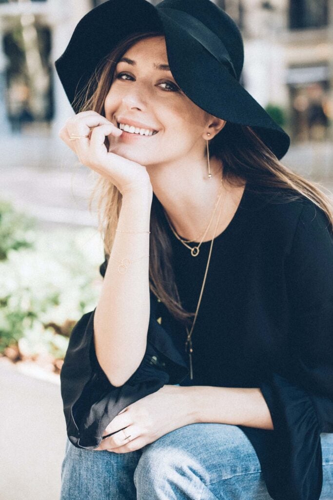 Bright smiling woman wearing a stylish black hat and casual outfit, embodying happiness and confidence, ideal for fashion and lifestyle photography.