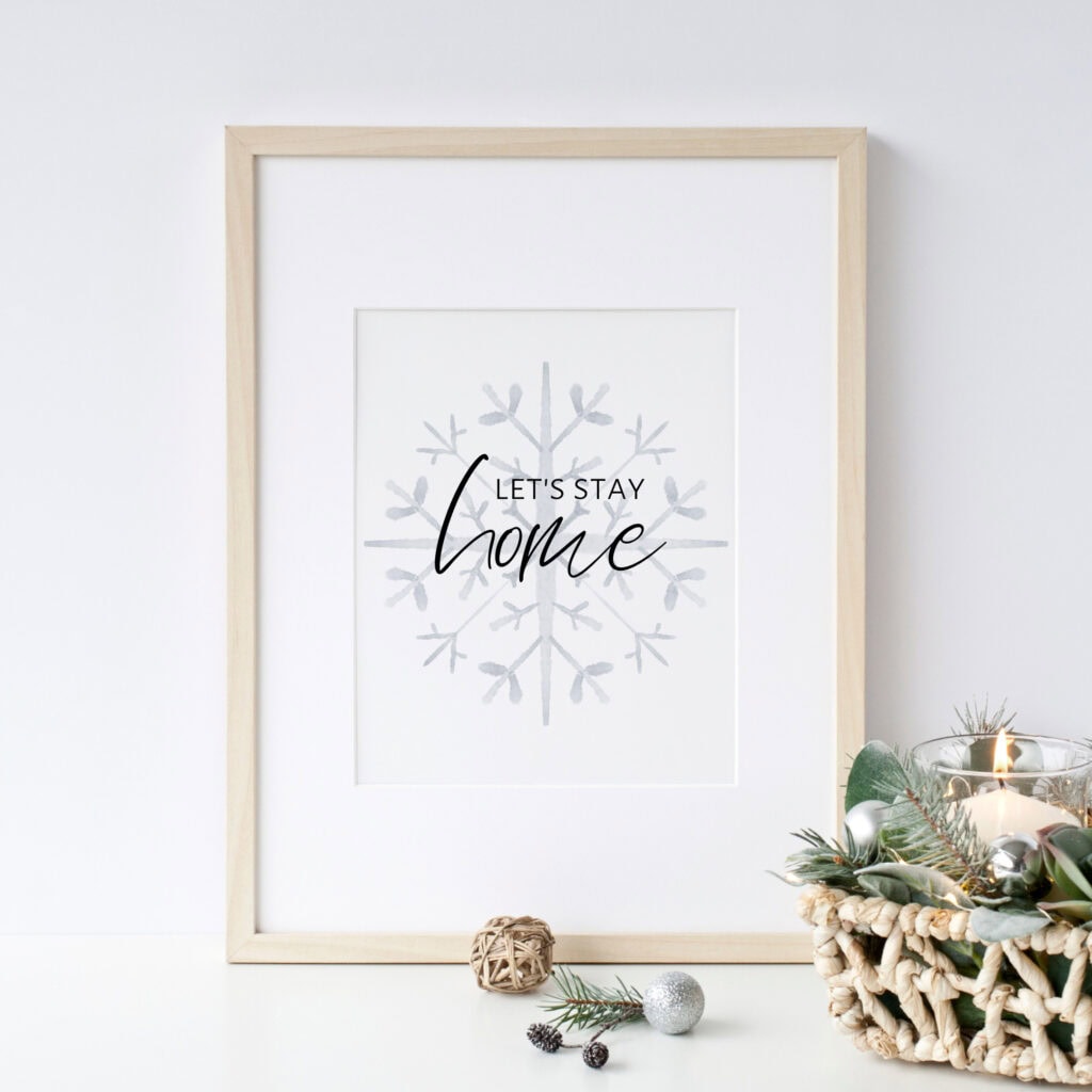 A cozy holiday-inspired framed art piece with the phrase "Let's stay home" and a snowflake design, perfect for festive Christmas decor and creating a warm, inviting atmosphere.