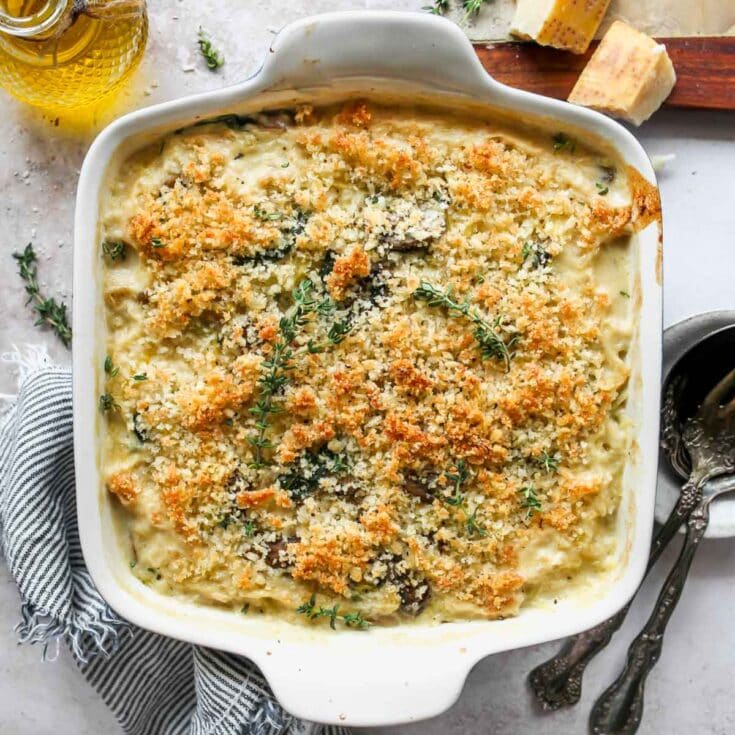 Creamy baked macaroni and cheese with a golden breadcrumb topping, garnished with fresh thyme, served in a white baking dish for comfort food lovers.