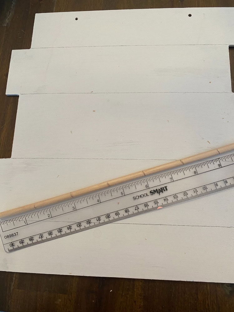 White painted wooden planks for furniture or decor projects, with a ruler for measurement, on a wooden surface.