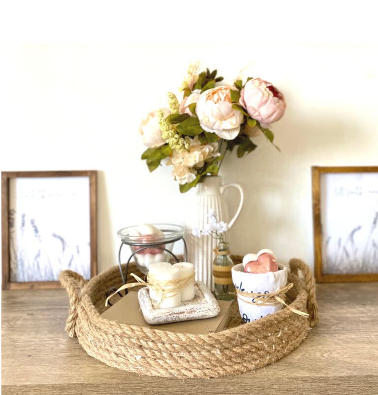 Love and faith-themed wall decor display with framed scripture, floral accents, candles, and eucalyptus on a rustic wooden mantel against a white brick wall.