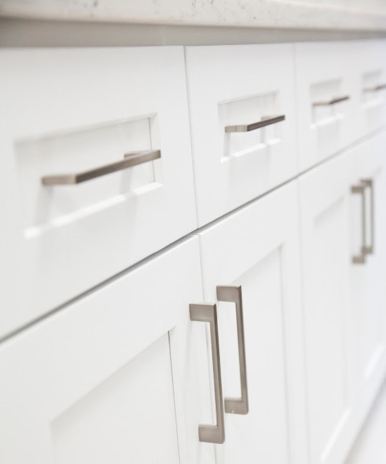 White kitchen cabinets with sleek silver handles, part of a modern and stylish kitchen design, emphasizing clean lines and functional cabinetry for a contemporary home.