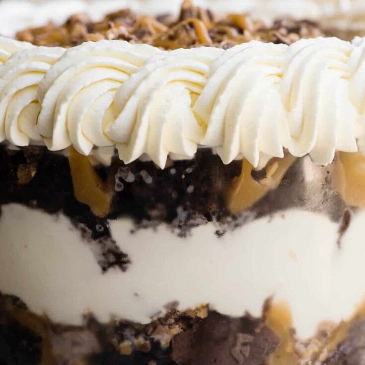 Decadent layered chocolate and vanilla cream dessert with whipped frosting, chocolate crumbles, and caramel drizzle, perfect for special occasions and sweet cravings.