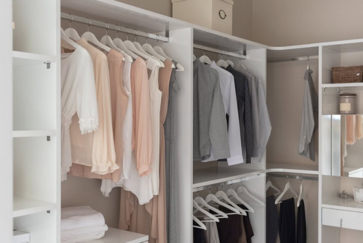 Closet organization with neatly hung clothing and shelves, showcasing a minimalist storage solution for wardrobe organization, ideal for a tidy and stylish bedroom space.