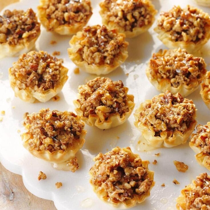 Savory baked crab rangoon dip bites on a white platter with crispy wonton cups filled with cheesy crab mixture.
