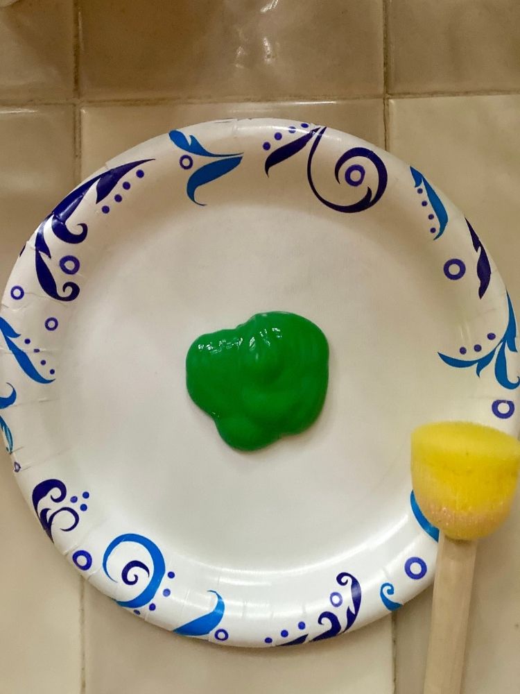 Green paint on paper plate with sponge brush