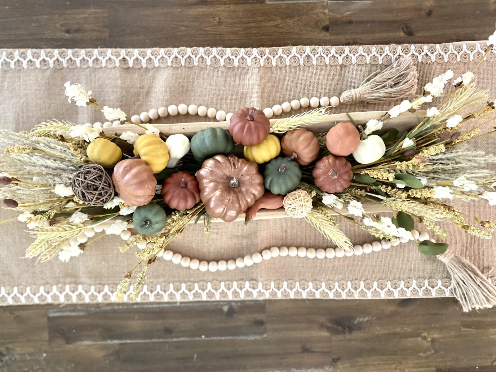 Colorful decorative pumpkins and autumn-inspired floral arrangement on a rustic table, perfect for fall decor and seasonal home accents.