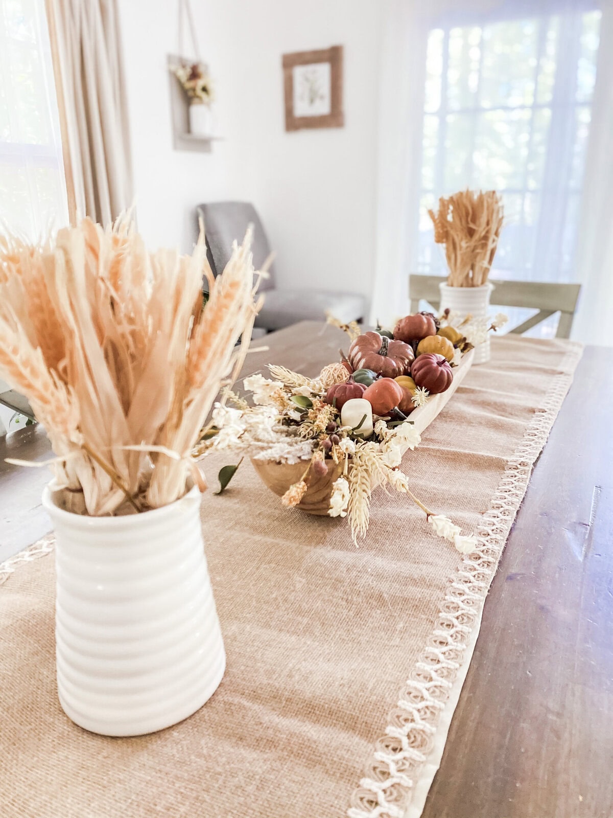 Rustic autumn table decor with dried flowers, pumpkins, and a neutral-toned table runner for cozy, farmhouse-inspired home styling.
