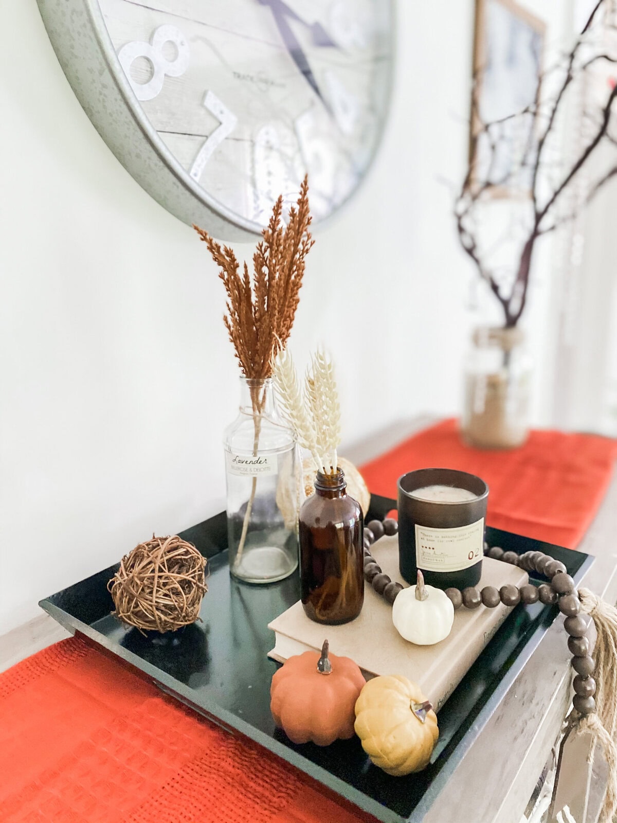 Vase with dried flowers and autumn-themed decor on a black tray, cozy home decor with pumpkins, candles, and neutral tones, perfect for fall ambiance and seasonal styling.