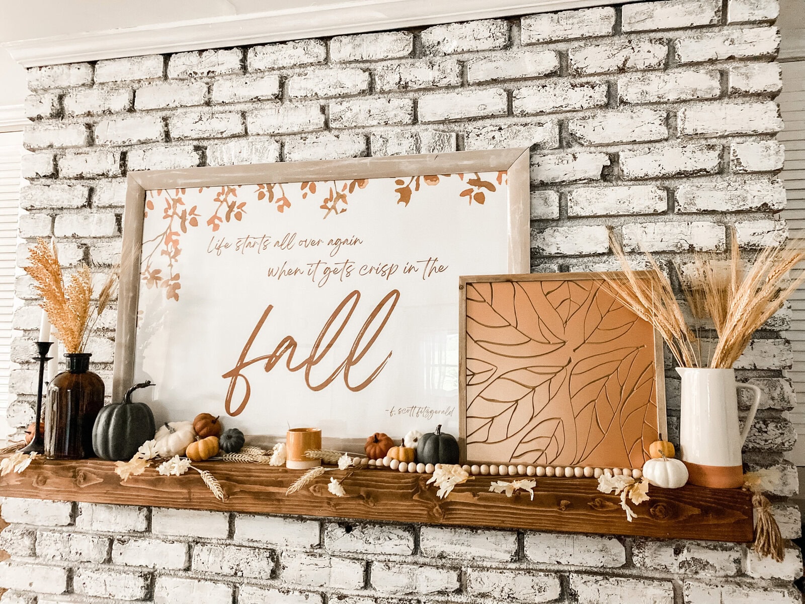 Pumpkin Halloween decor on white fireplace mantel with natural fall accents and a large round mirror above, creating a cozy and festive autumn ambiance for home interior decor.