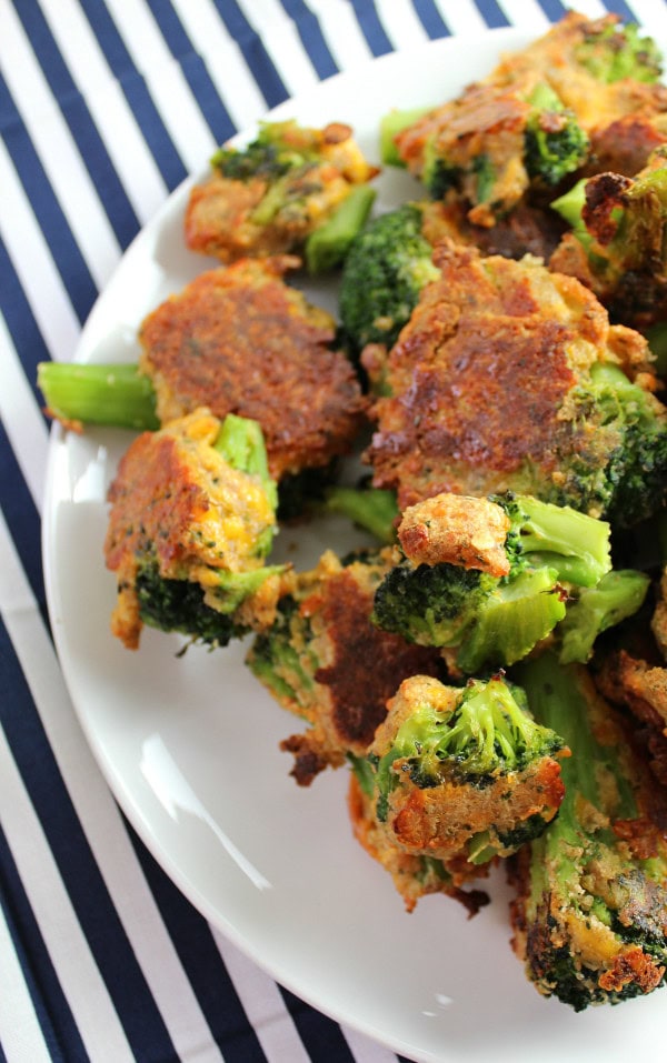 Crispy breaded broccoli bites with golden coating and vibrant green florets, served on a white platter perfect for healthy snacks or appetizer recipes.