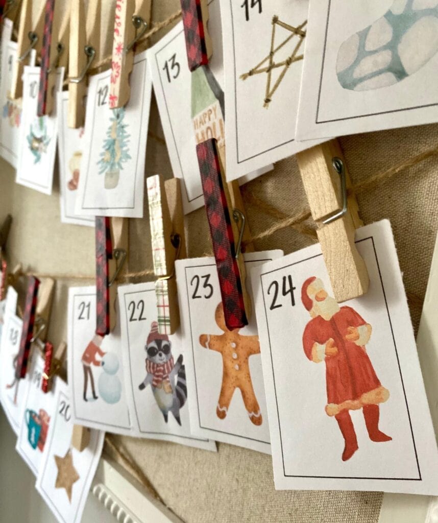 Christmas advent calendar with festive illustrations and numbered paper cards, decorated with clothespins and ribbons for holiday countdown.