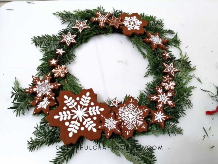 Handmade Christmas gingerbread cookie wreath decorated with white icing snowflakes and stars, featuring festive evergreen branches for holiday home decor.