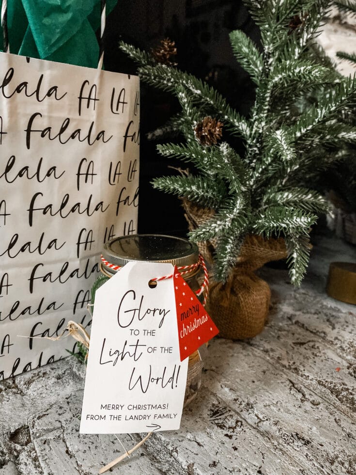 Festive holiday decor with Christmas tree, lantern with holiday tag, gift bag with handwritten style text, cozy rustic setting, seasonal decorations, and holiday greetings, perfect for Christmas celebration, gift-giving, and festive ambiance.