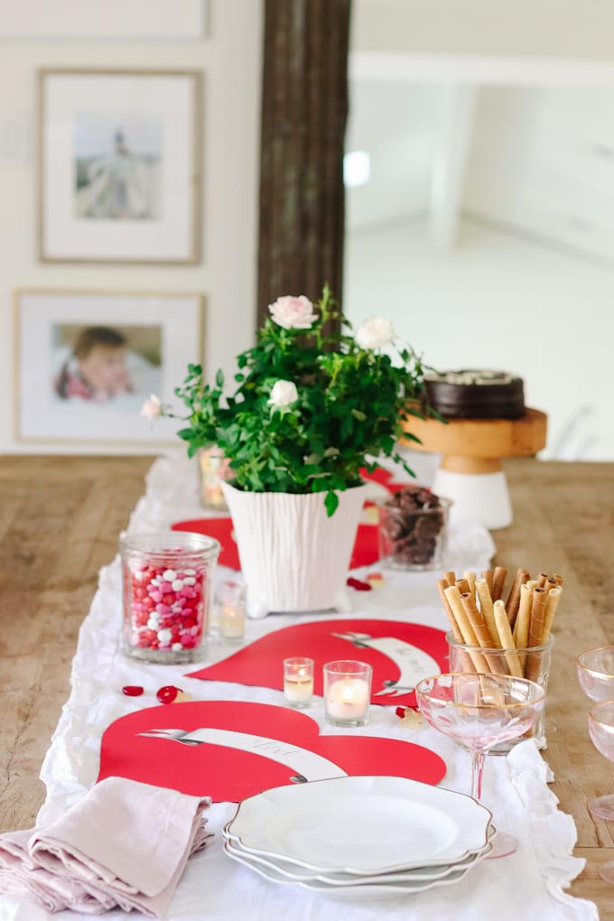 Bright, romantic table with pink and red accents, fresh flowers, candles, and themed tableware, perfect for celebrating love and special moments.