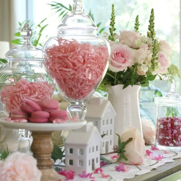 Pink candy and macarons displayed with floral arrangements for elegant celebration decor.