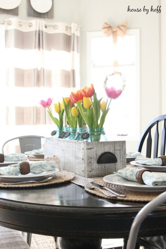 Bright and fresh tulips in a vintage teal jar serve as a charming centerpiece in a cozy farmhouse dining room, perfect for spring gatherings and adding natural beauty to your home decor.