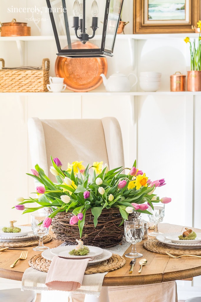 Elegant spring table decor with tulips in a rustic woven basket, perfect for Easter or spring celebrations. Bright, fresh flowers create a cheerful and inviting dining setting.