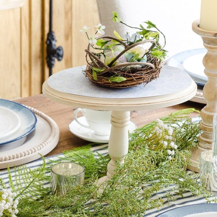 Delicate floral arrangement with white flowers and greenery displayed on a rustic wooden table for spring or summer decor.