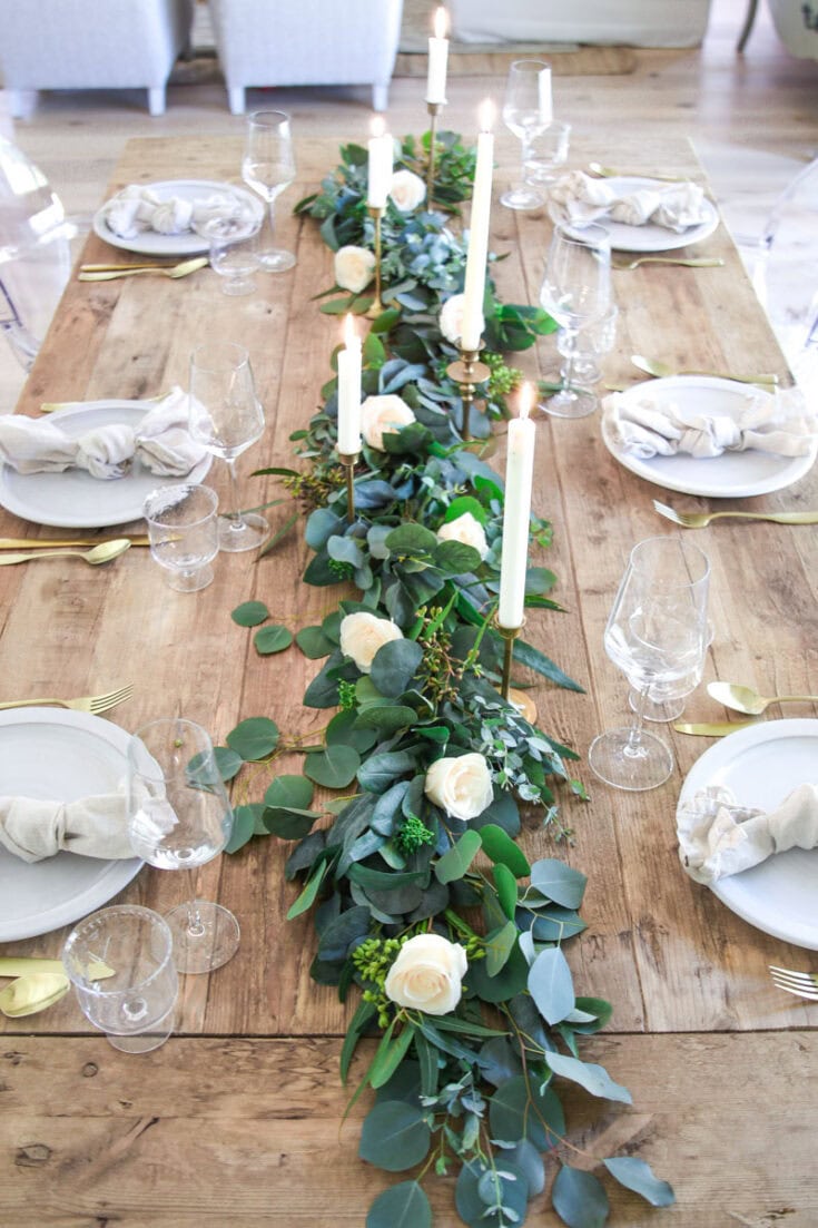 Luxurious wedding table centerpiece with white roses, lush greenery, and elegant candles for a romantic celebration. Decorated with modern candle holders, perfect for wedding receptions, bridal showers, and special events.