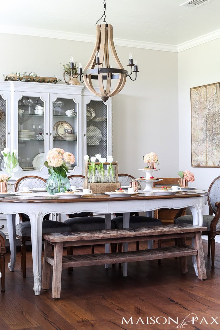 Elegant farmhouse dining room featuring vintage furniture, floral arrangements, and rustic accents for cozy home decor.