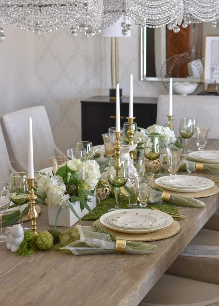 Luxurious elegant dining table decorated with white hydrangea flowers, gold candlesticks, white candles, and green glassware for a sophisticated event or wedding celebration at A Hundred Affections.