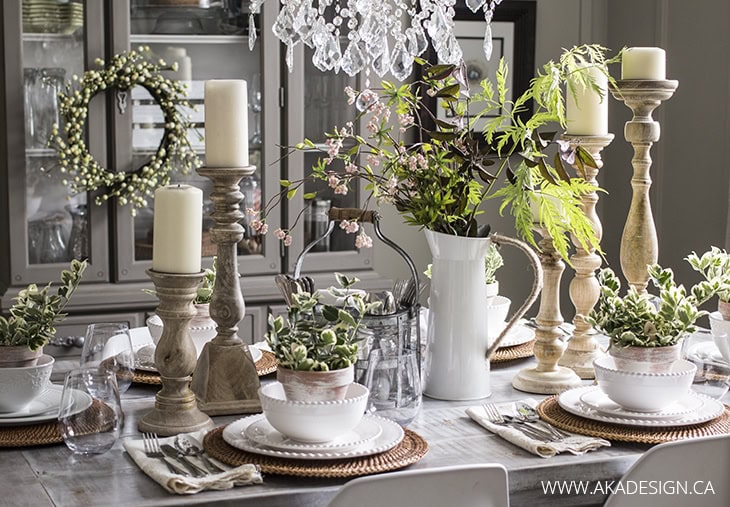 A beautifully decorated dining table featuring candles, lush greenery, and rustic tableware perfect for creating a cozy, sophisticated ambiance. Ideal for farmhouse or vintage-inspired decor.