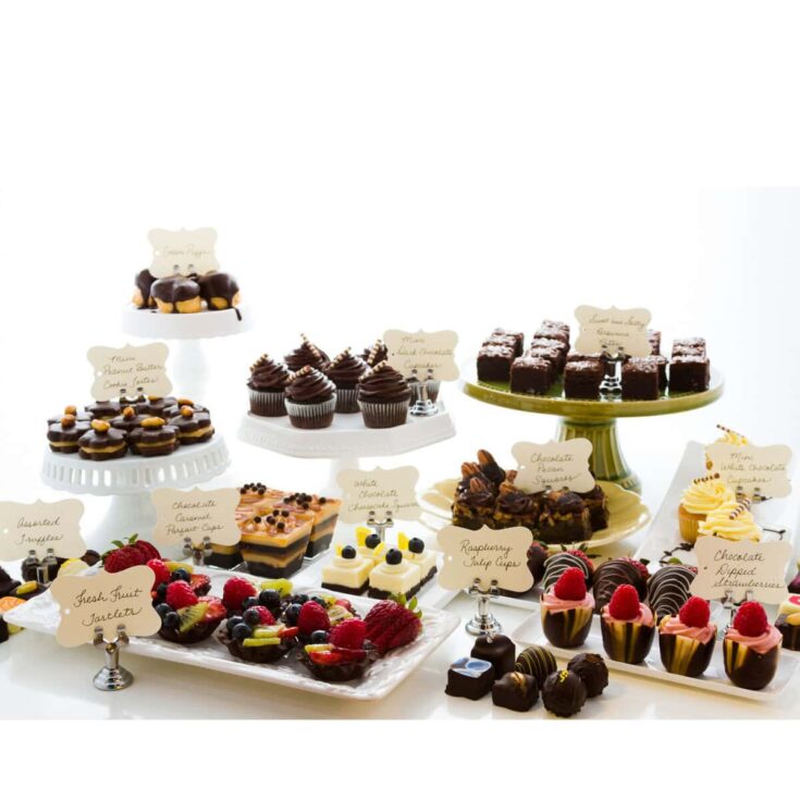 Delicious assortment of gourmet desserts including cupcakes, chocolate squares, fruit tarts, and mini pastries displayed on elegant cake stands and trays at A Hundred Affections.