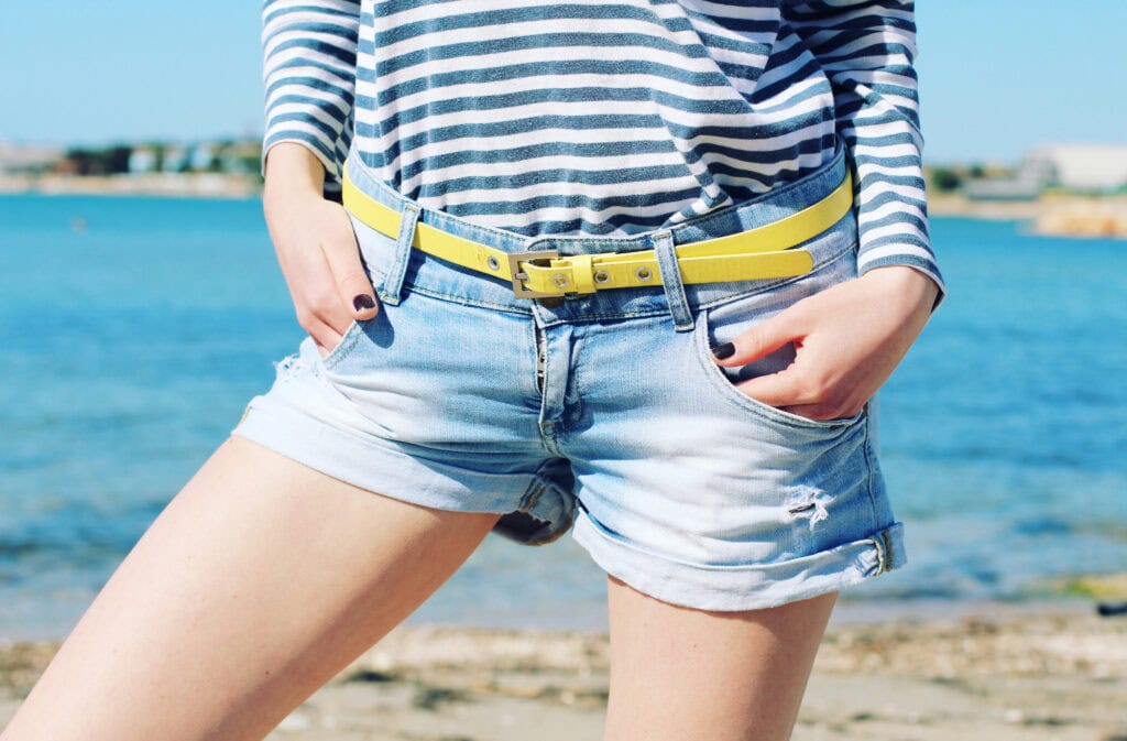 Bright yellow belt paired with striped top and denim shorts, casual summer beach style.