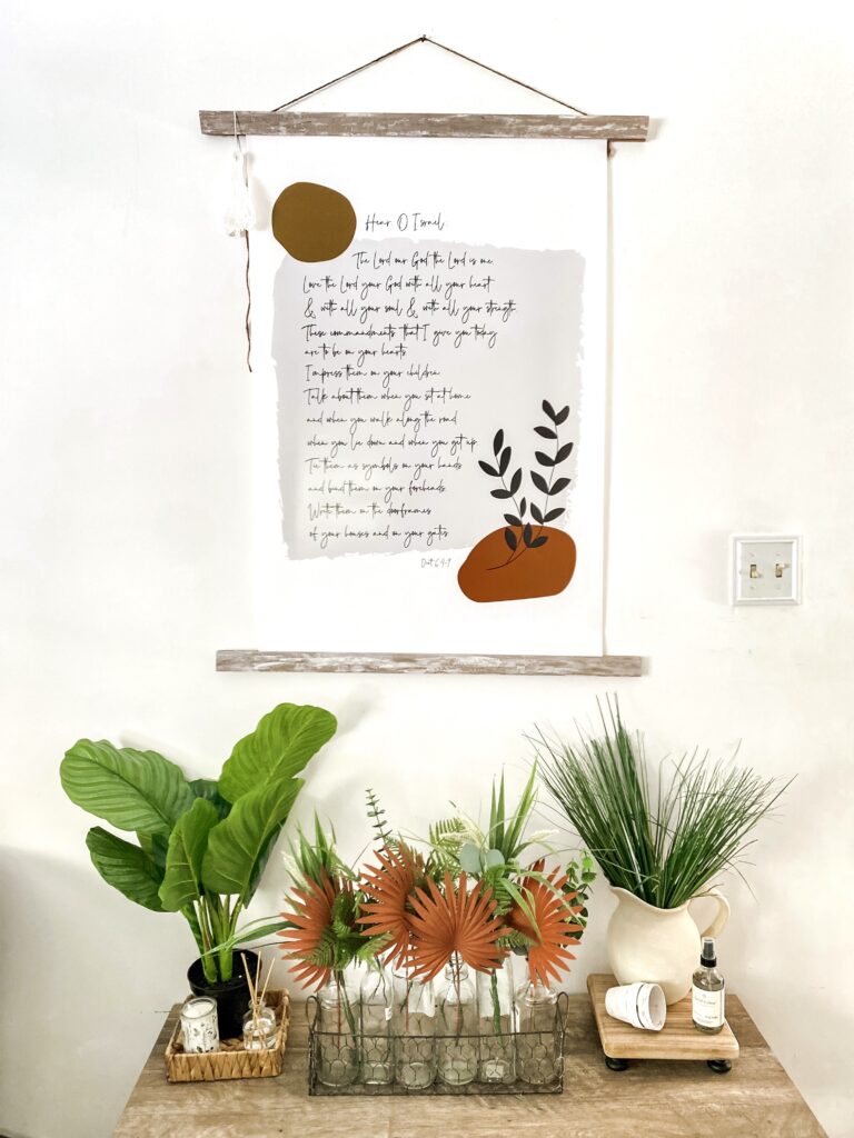 Cozy living room with neutral tones, wooden accents, and greenery, showcasing stylish wall decor and a comfortable beige sofa. Perfect for creating a warm, inviting home atmosphere.