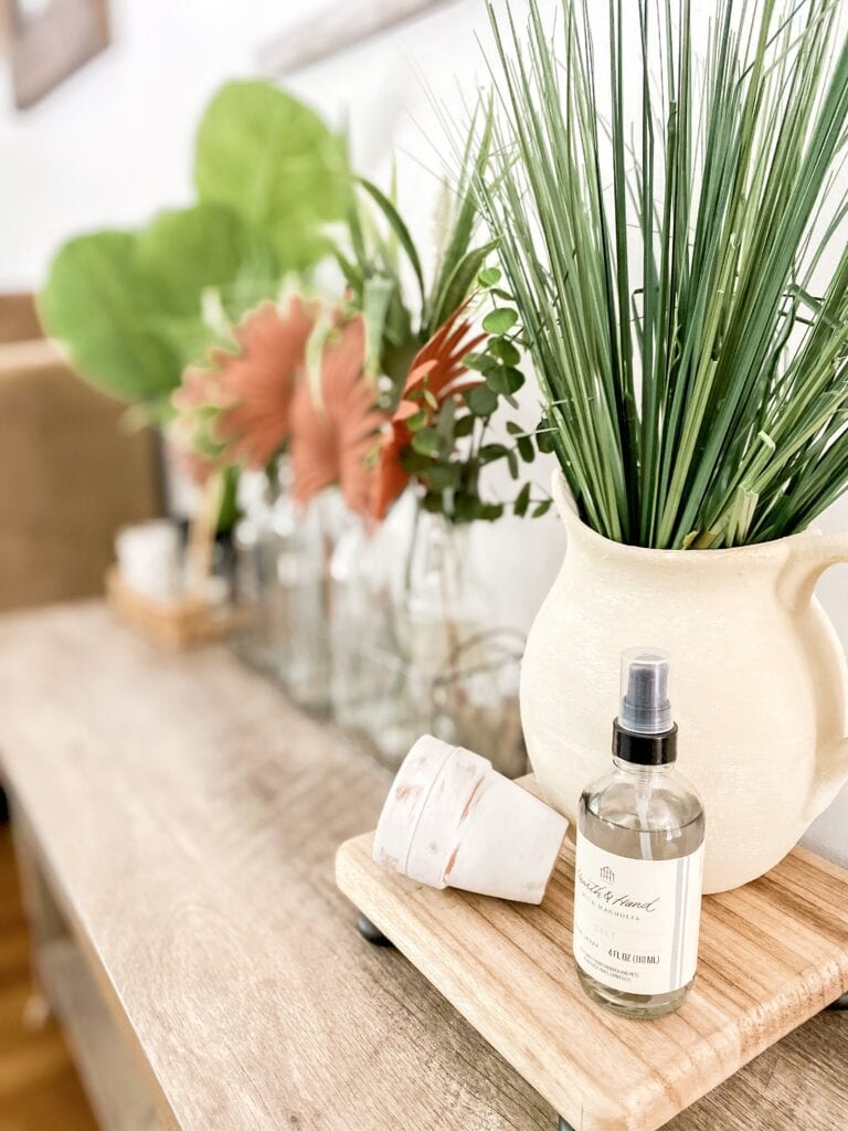 Cozy living room with neutral tones, wooden accents, and greenery, showcasing stylish wall decor and a comfortable beige sofa. Perfect for creating a warm, inviting home atmosphere.