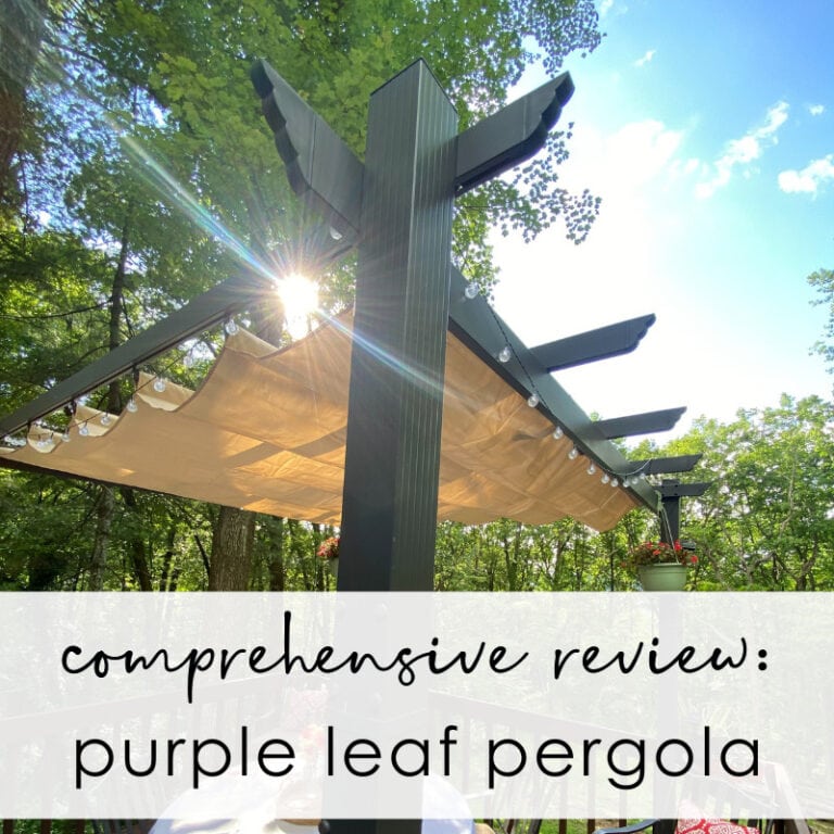 Elegant outdoor purple leaf pergola with shaded canopy and string lights, situated in lush green wooded area, perfect for garden entertainment and relaxation.