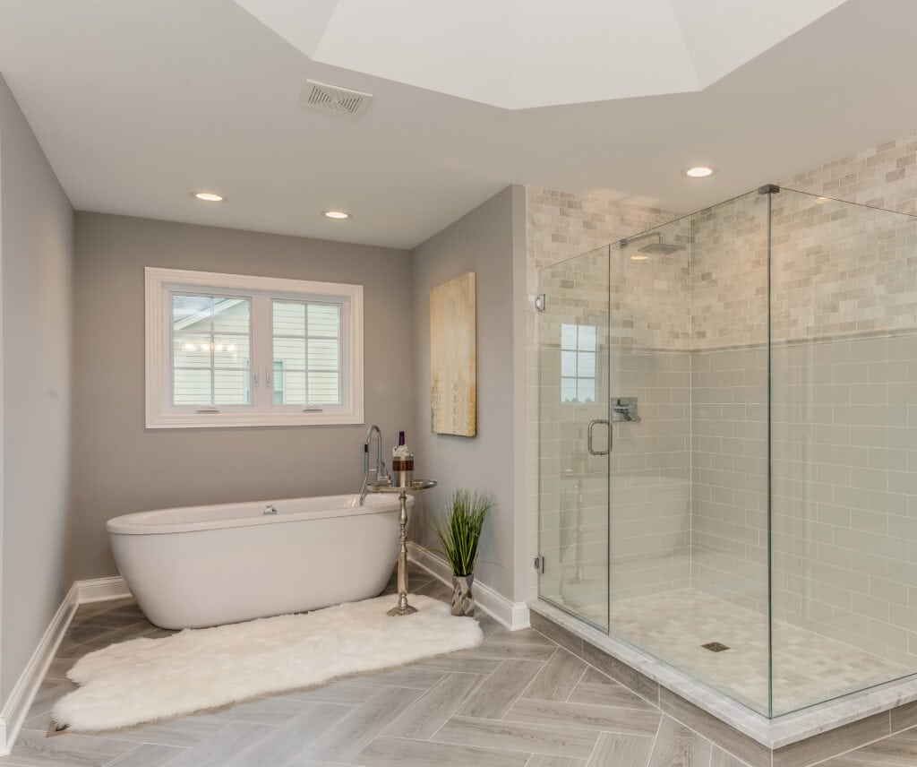 Luxurious modern bathroom with a spacious glass-enclosed shower, elegant white marble accents, a freestanding bathtub, and natural light from multiple windows, perfect for relaxation.