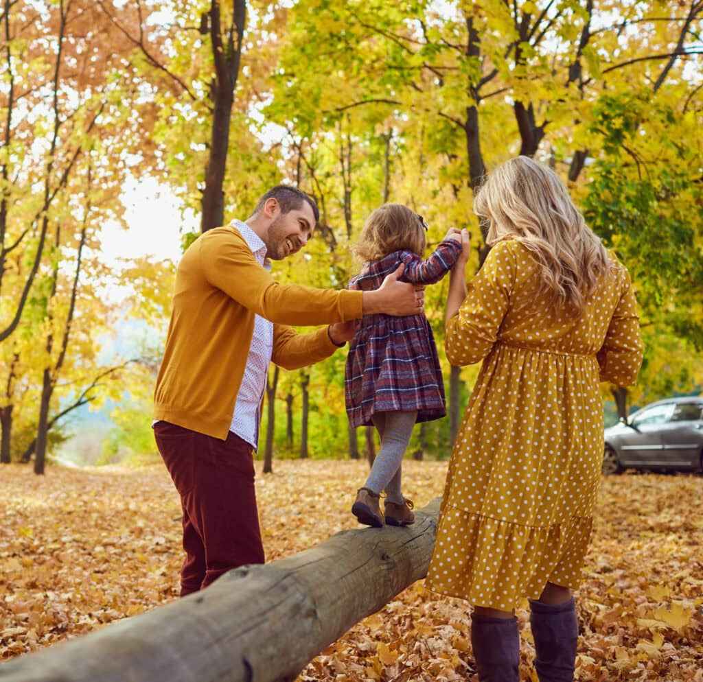 family in fall with daughter on log