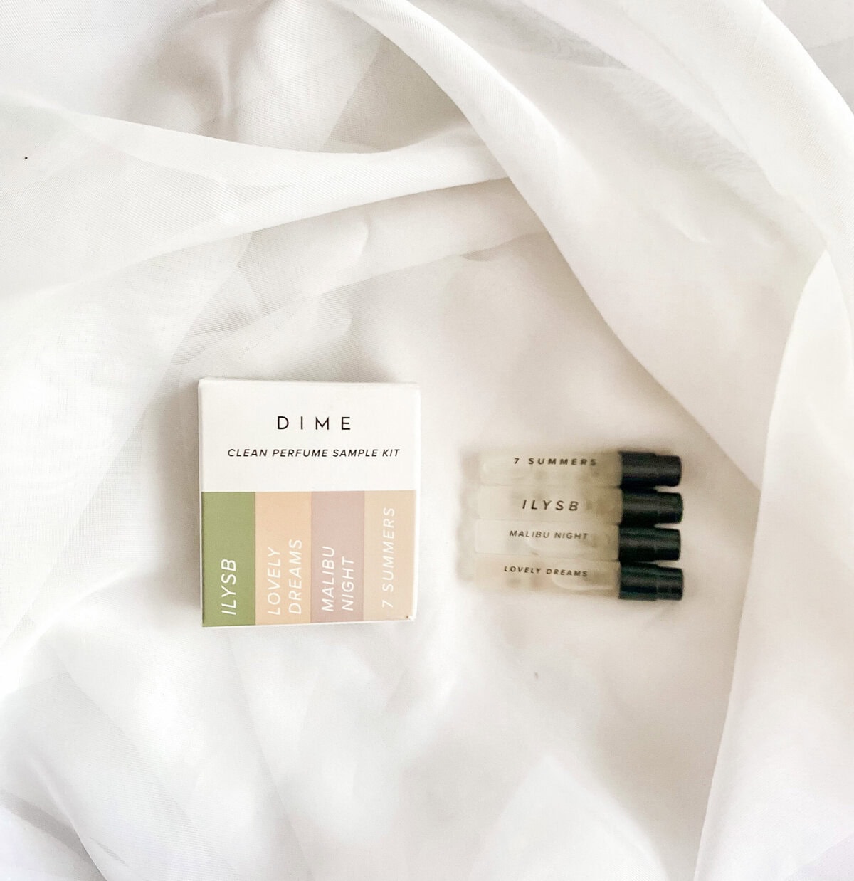 Delicate perfume sample kit from A Hundred Affections with five fragrance vials and a packaging box on white fabric.