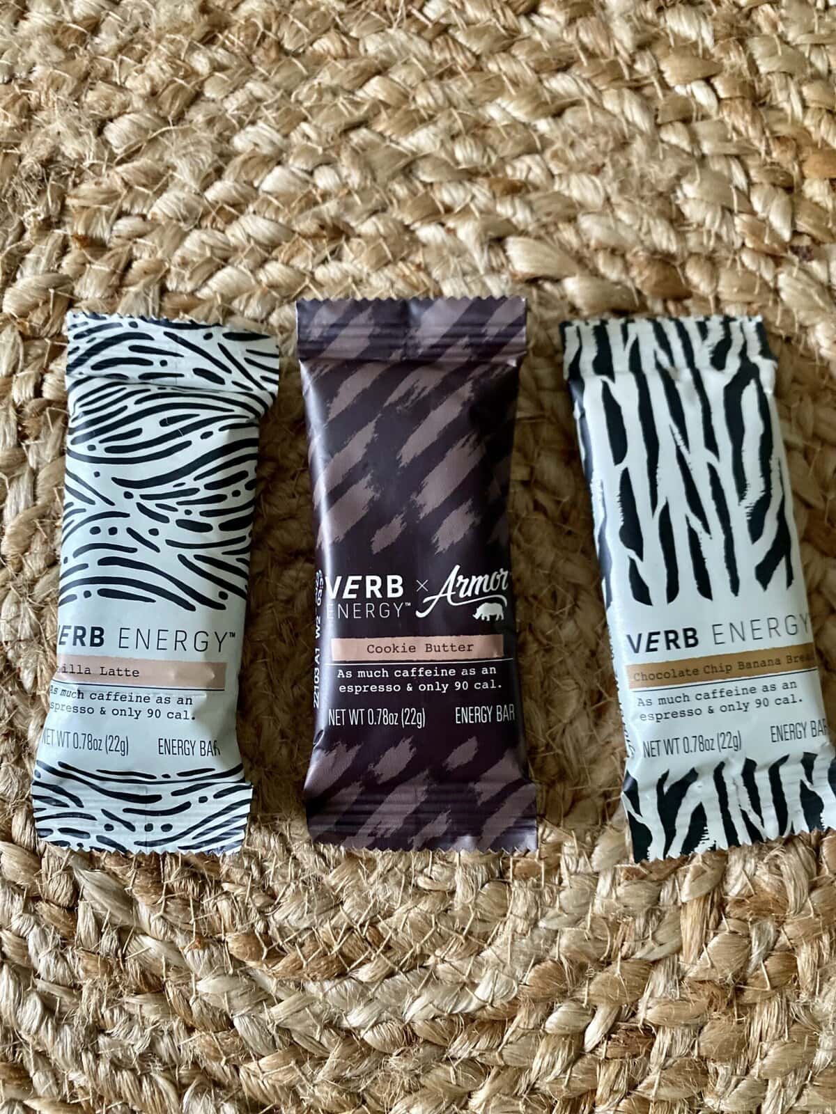 Energy bars with zebra and animal print packaging on a woven natural fiber background.