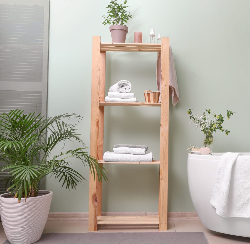 Natural wood bathroom shelving unit with towels and toiletries in a modern spa setting.