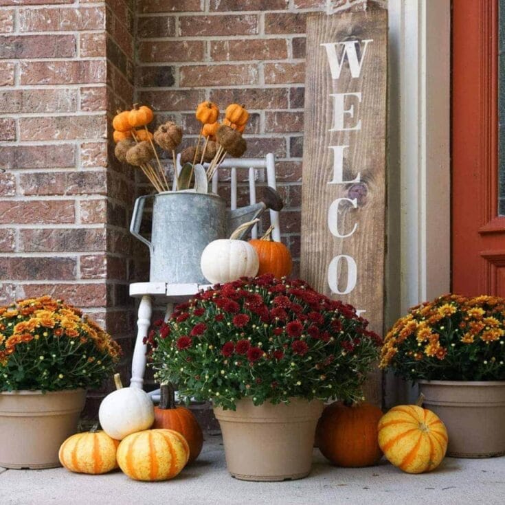Pumpkin and mum fall porch decor with a rustic watering can, wooden "Welcome" sign, and cozy autumn accents for welcoming guests.