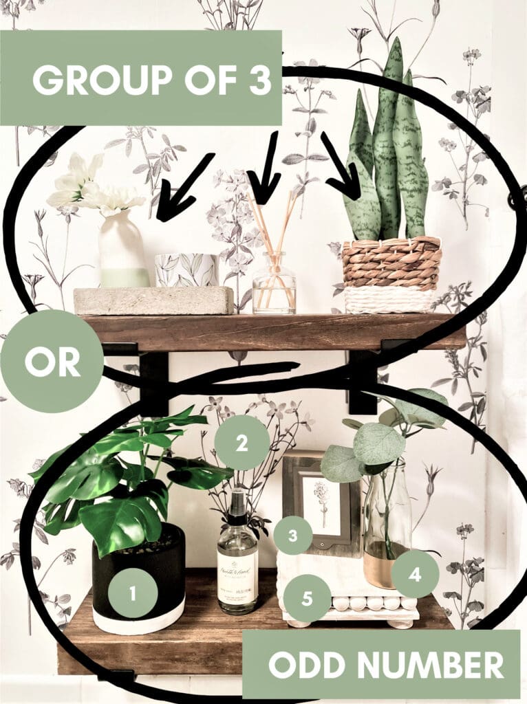 Vase with white flower, potted green Monstera plant, reed diffuser, framed botanical print, decorative eggs on a wooden shelf with floral wallpaper background.