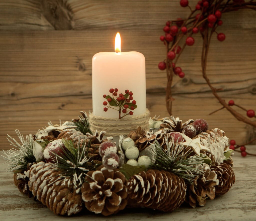 Pinecone and Christmas wreath with lit candle, holiday decorations emphasizing winter and festive Christmas spirit.