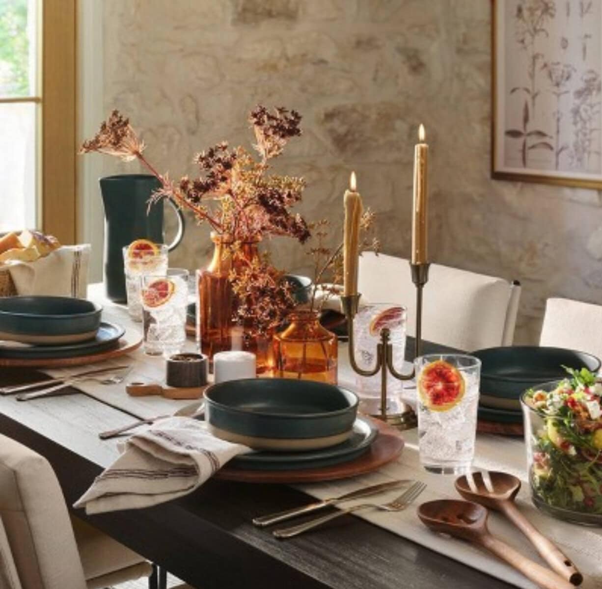 Rustic dining table setting with black ceramic plates, floral centerpiece, candles, and glassware for a cozy, elegant dinner. Perfect for farmhouse-inspired home decor and entertaining guests.
