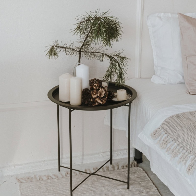 minimalist bedside table with candles and pine branch for minimalist christmas decor