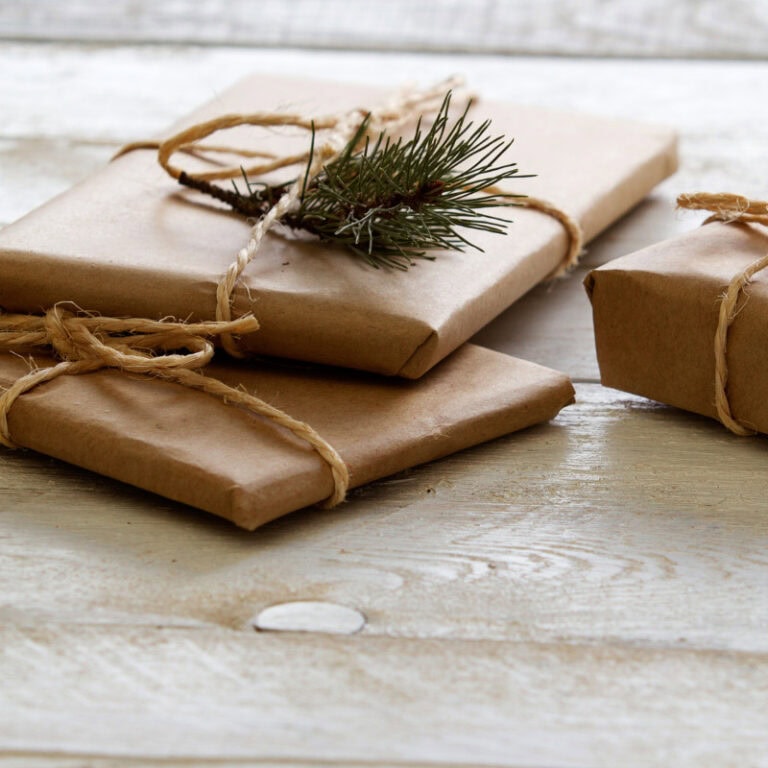Handwrapped Christmas presents with brown kraft paper, twine bows, and pine sprigs, perfect for holiday gift-giving and seasonal decor.