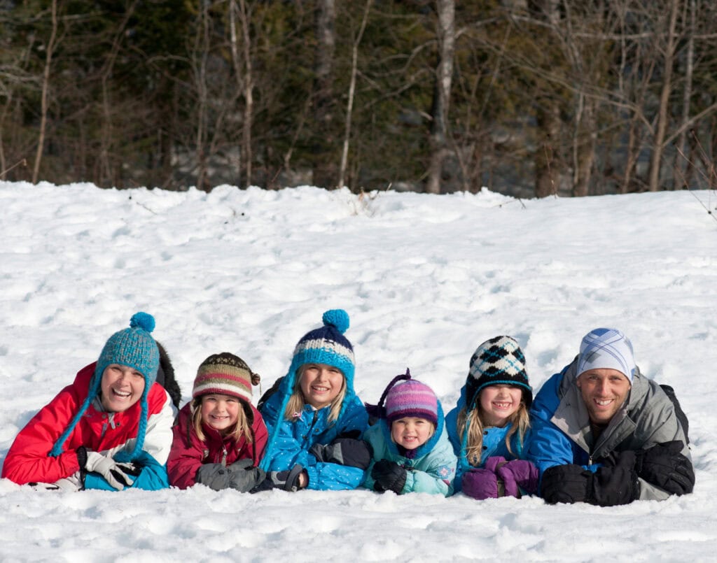 family laying in snow for winter photoshoot
